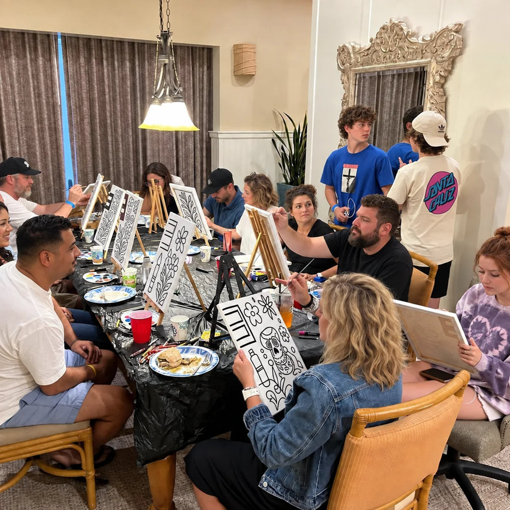 People painting pre-drawn outline canvases around a dining table