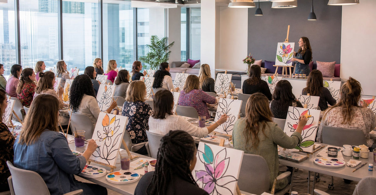 Employees painting outline canvases at a corporate paint night in a modern office