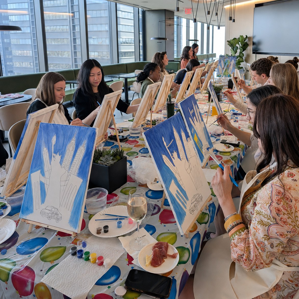 Three colleagues painting outline canvases together at a conference table