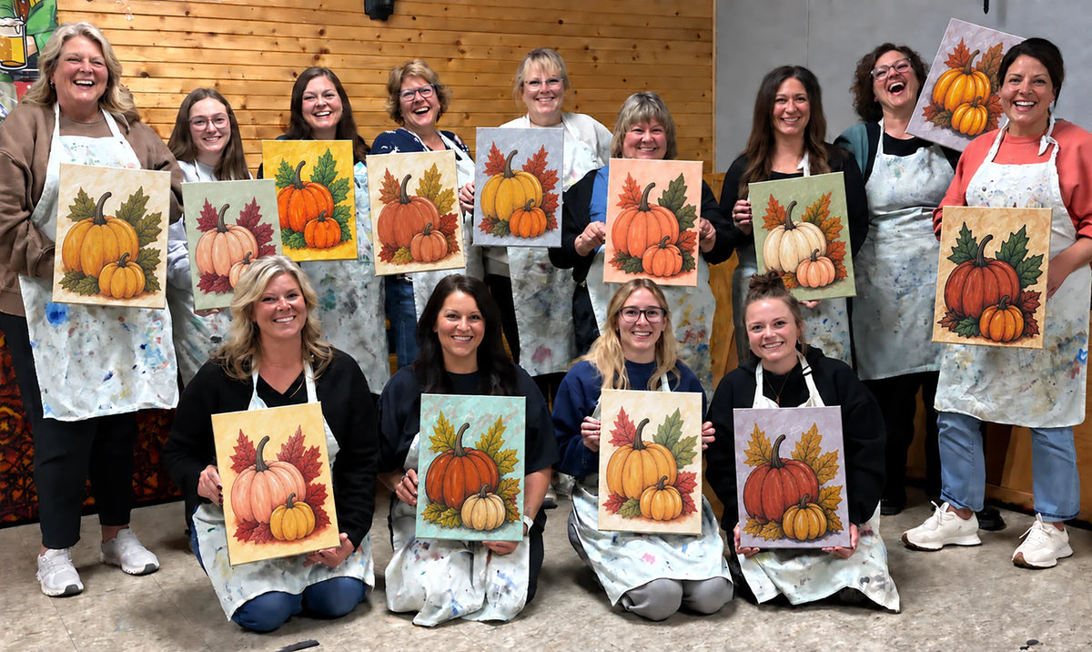 Friends holding colorful pumpkin paintings after a paint party